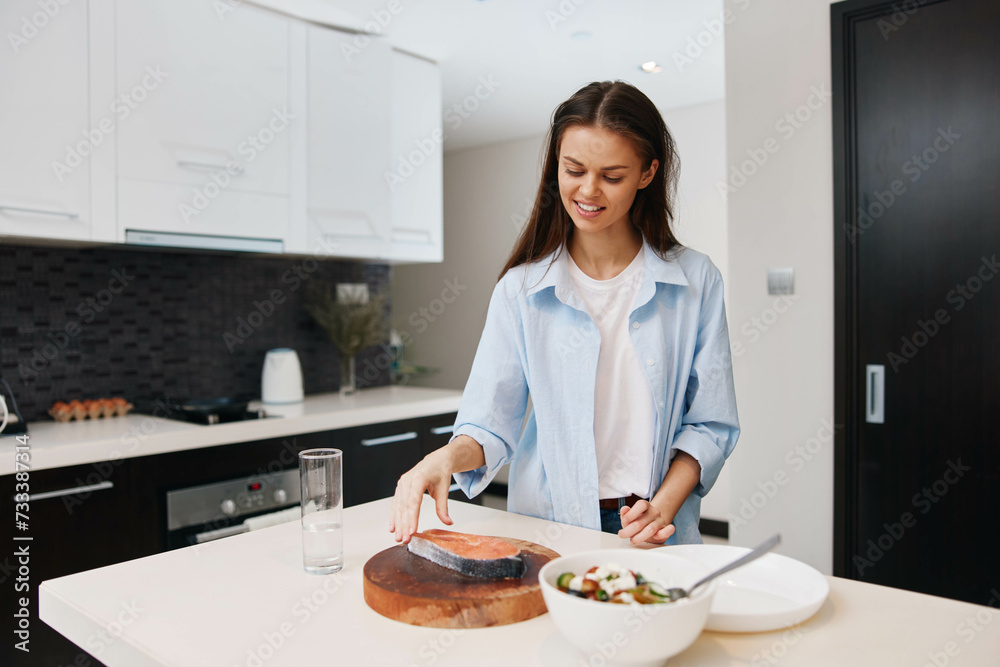 Happy woman cooking in contemporary kitchen at home, preparing healthy food with smile on face, modern lifestyle concept