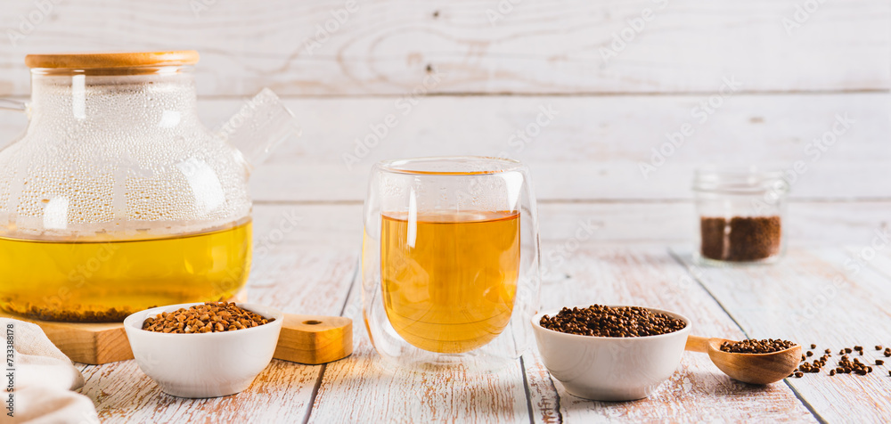 Fresh buckwheat tea in a glass, teapot and granules in a bowl on the table web banner Fresh buckwheat tea in a glass, teapot and granules in a bowl on the table web banner