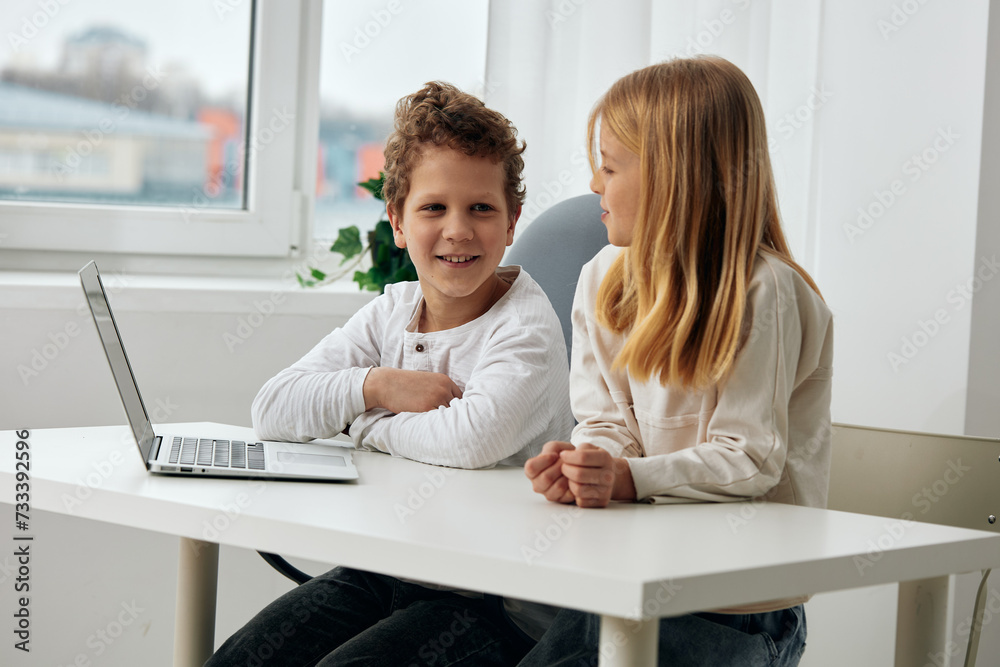 Happy siblings studying at home using laptops for online learning Happy siblings studying at home using laptops for online learning