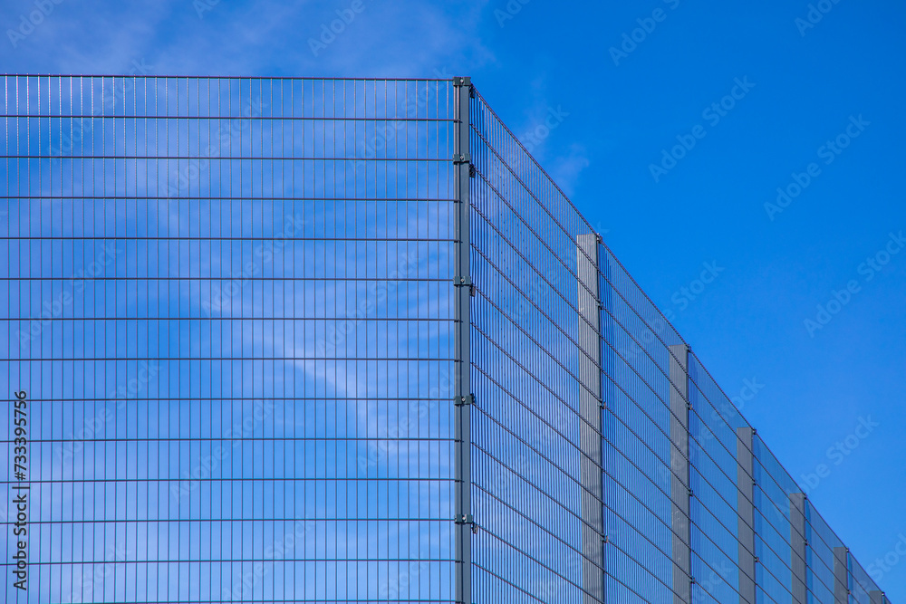 Modern high metal fencing of playground against blue sky background. Diagonal, copy space Modern high metal fencing of playground against blue sky background. Diagonal, copy space