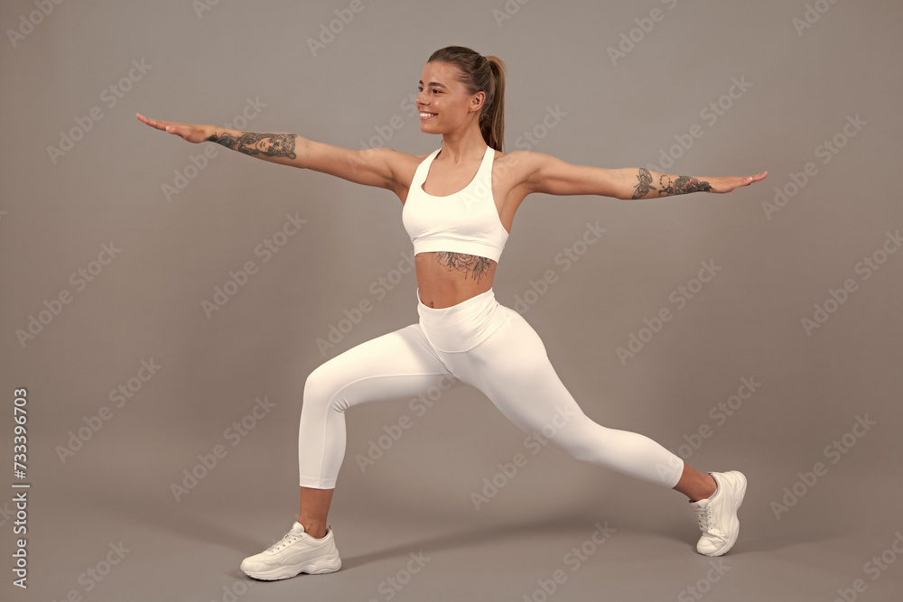Fototapeta premium Sporty strong cheerful young woman posing on gray isolated background. Caucasian female athlete, muscular, sportive woman. Concept of youth healthy lifestyle.