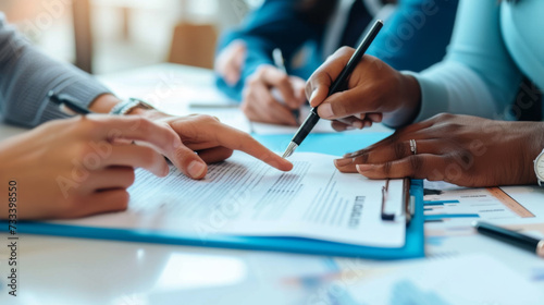 A team of professionals is engaged in a business meeting, with hands pointing and writing on documents, emphasizing collaboration and strategic planning.