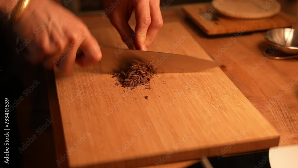 Cocoa making. Chef cuts cocoa on the wooden table with a kitchen knife. Chef cooking closeup cinematic 4k 10 bit. Chopped dark cocoa on the kitchen board. Mood light. Hand cutting cocoa in restaurant. Cocoa making. Chef cuts cocoa on the wooden table with a kitchen knife. Chef cooking closeup cinematic 4k 10 bit. Chopped dark cocoa on the kitchen board. Mood light. Hand cutting cocoa in restaurant.