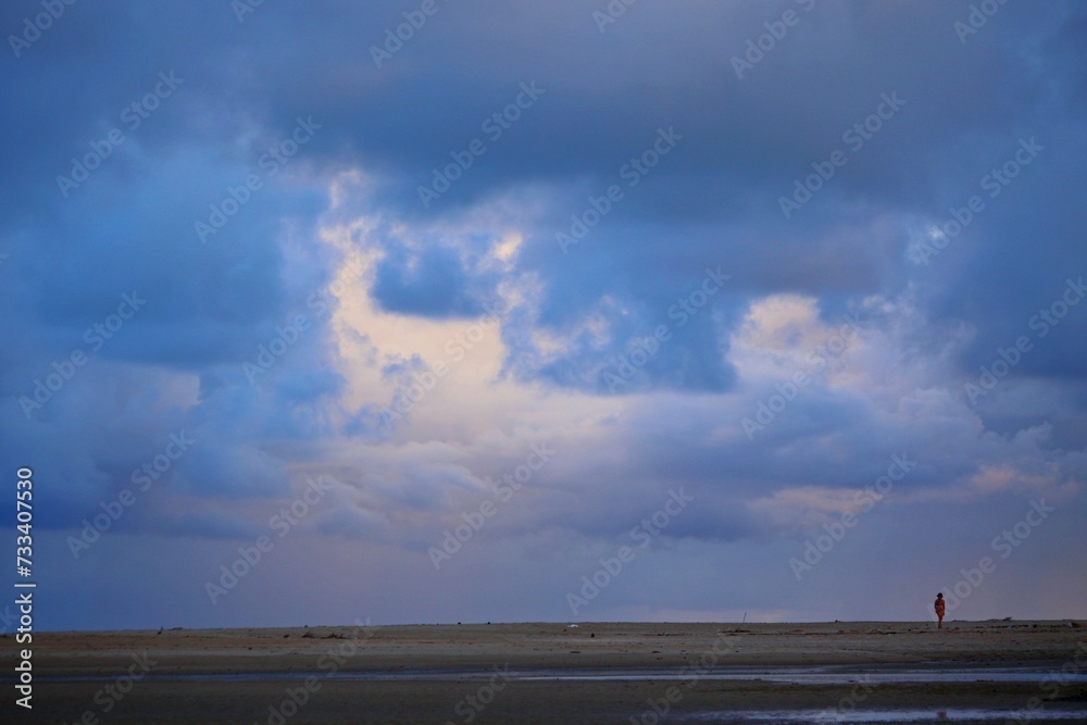 Blue sunrise on Japaratinga beach, Alagoas state, Brazil. First day light on the sea and sky. Clouds and sun light reflections.