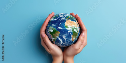 Hands cradle a realistic miniature Earth against a serene blue background, symbolizing care and stewardship for our planet.