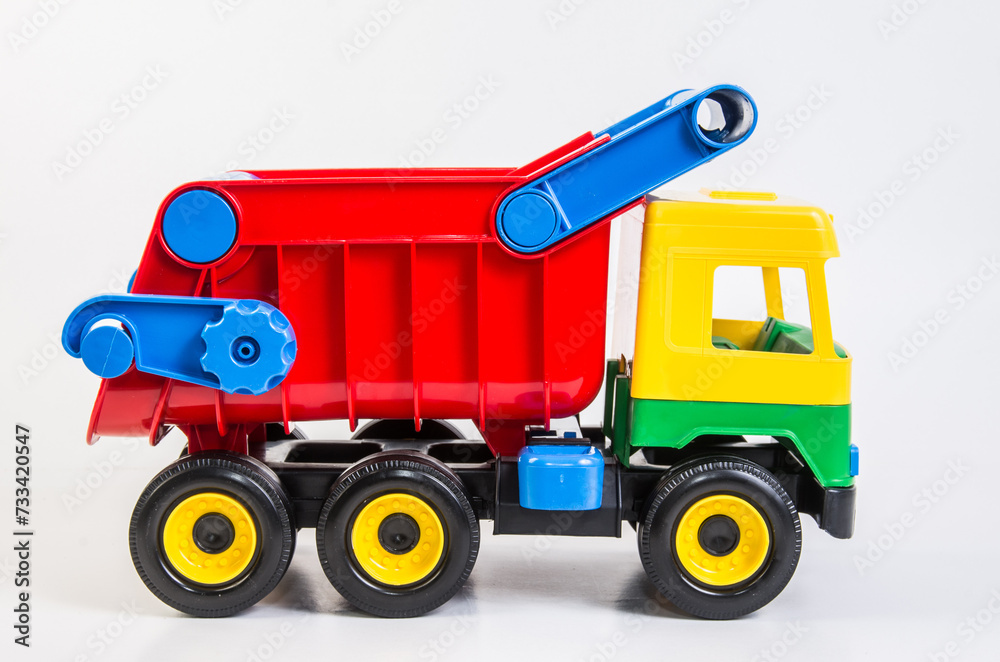 Multi-colored plastic toy trucks for children's games on a white background. Dumper.