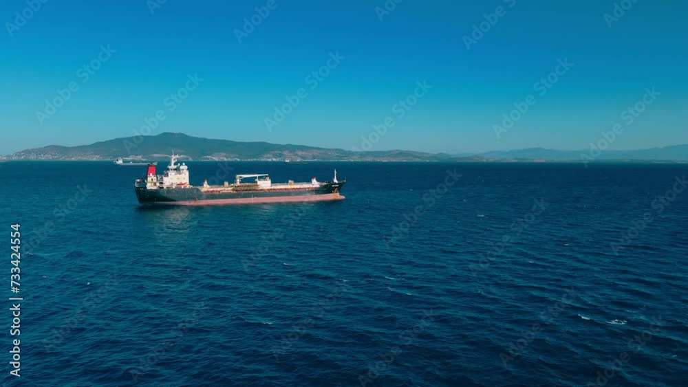 Petrochemical oil product cargo ship carrier at anchorage in sea waiting loading on industrial port terminal. Aerial view Petrochemical oil product cargo ship carrier at anchorage in sea waiting loading on industrial port terminal. Aerial view