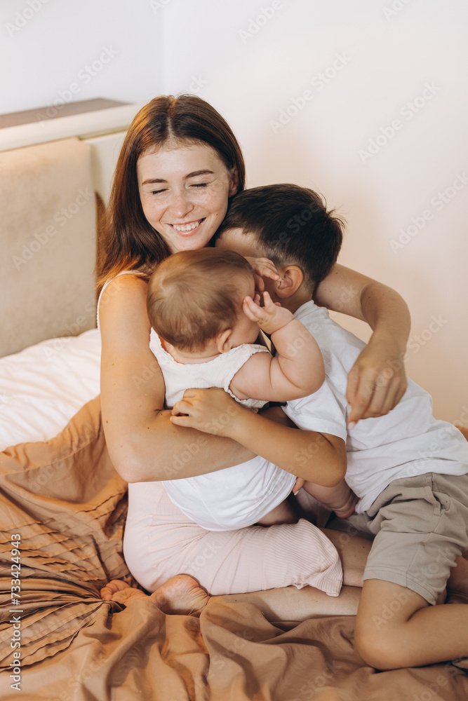 Happy young mother spending time with her children in the bedroom Happy young mother spending time with her children in the bedroom