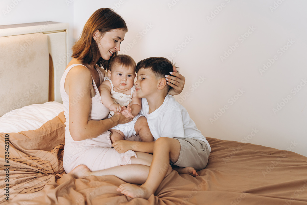 Happy young mother spending time with her children in the bedroom