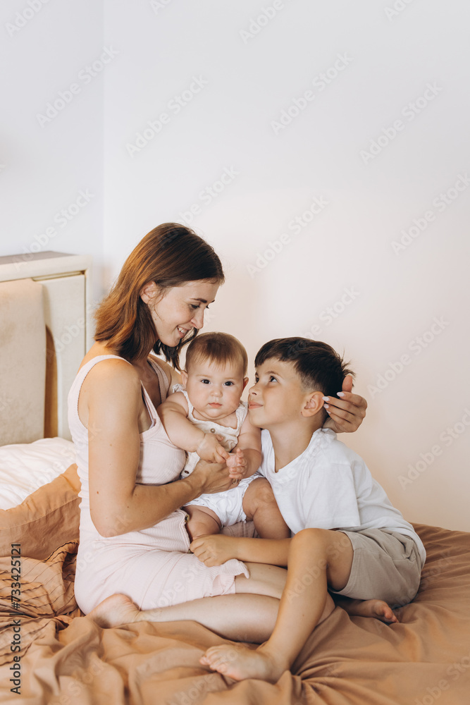 Happy young mother spending time with her children in the bedroom Happy young mother spending time with her children in the bedroom