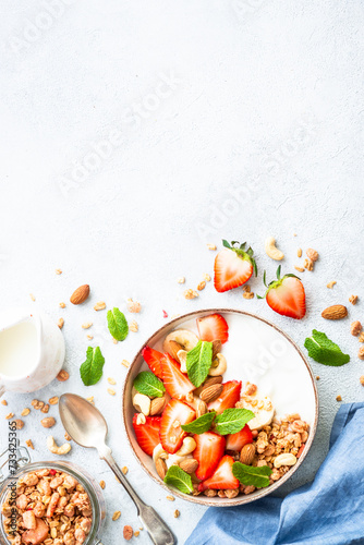 Yogurt with granola and strawberries on white background. Healthy snack or breakfast. Top view with copy space.