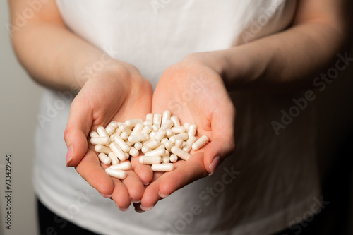Female hands hold handful of white medicine tabs pills, concept of wellness