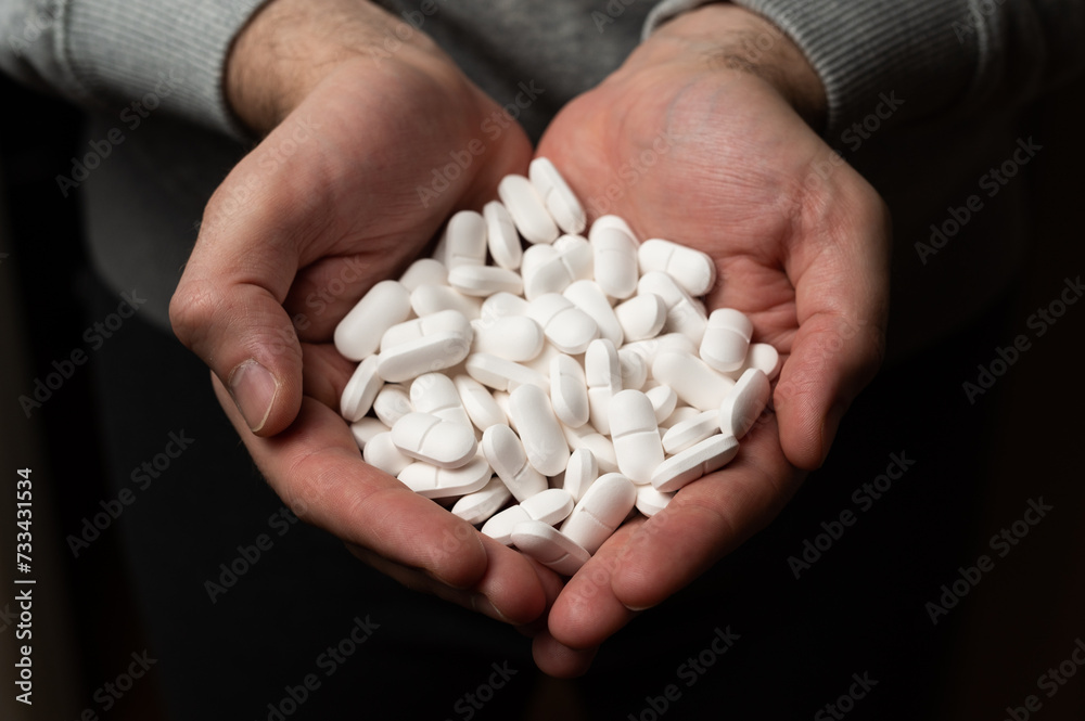 Male hands hold handful of white medicine tabs pills, concept of wellness Male hands hold handful of white medicine tabs pills, concept of wellness