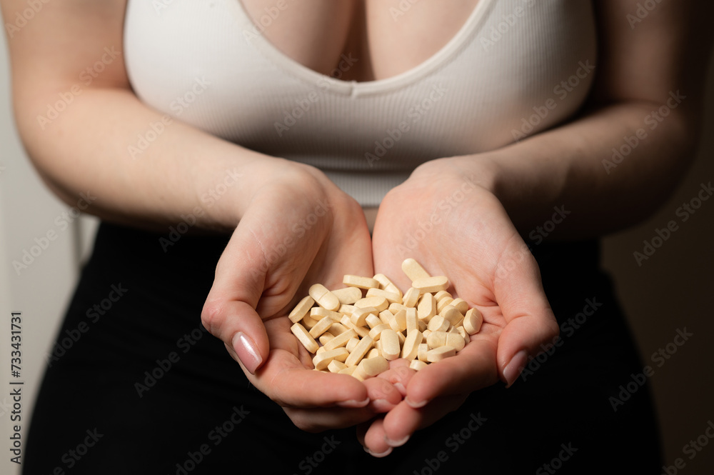 Obraz premium Female breast health awareness concept: woman hands hold handful of supplements for breast support and cancer prevention