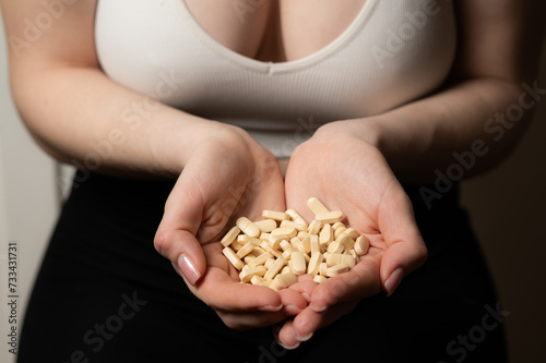 Female breast health awareness concept: woman hands hold handful of supplements for breast support and cancer prevention