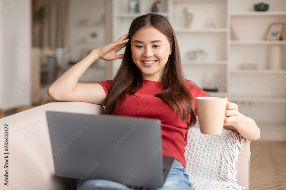 Domestic Leisure. Young Asian Woman Relaxing With Coffee And Laptop At Home