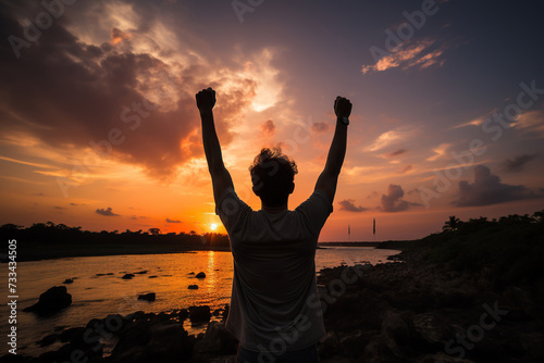 Silhouette of a happy man with his hands raised up against the backdrop of a sunset or dawn. Generated by artificial intelligence