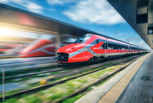 Red high speed train in motion on the railway station at sunset © den-belitsky