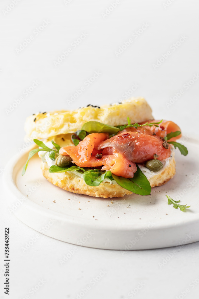 Homemade bagel sandwich with smoked salmon, cream cheese, capers and spinach for healthy breakfast isolated on white background text space