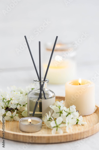 Aromatherapy  home decor concept. Glass perfume bottle  elegant composition with spring flowers. Burning candles  spa setting  essential oils  organic pure aromatic ingredients  atmosphere of relax