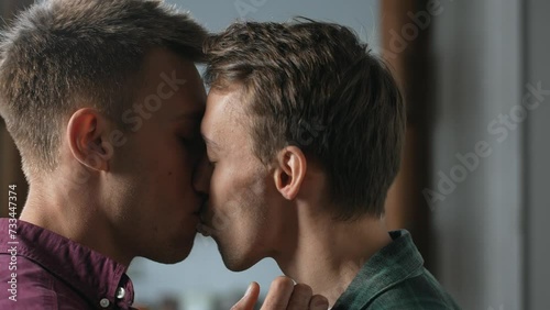 Authentic close up of affectionate attractive homosexual couple with eyes closed passionately kissing, expressing love, sexual attraction and strong relationship indoors. High quality 4k footage