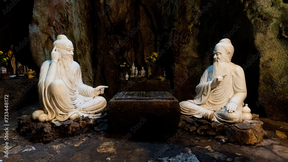 Buddha statues sitting in front of a board in the marble mountains in Vietnam