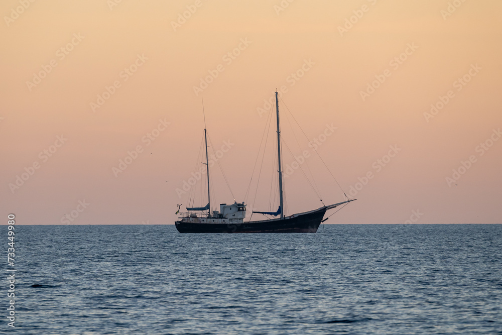 A sail boat alone at sea, at sunset. High quality photo