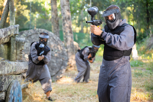 Man eliminating opponents on paintball field. Man in protective outwear and helmet targeting with paintball marker.