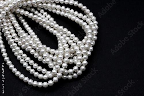 Beautiful and round Chinese freshwater pearls on a black background, ready to be made into necklaces on a string and sold in jewelry store. A popular wedding jewel for the bride.