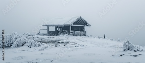 A winter day in Krkonose national park where there is a frozen shelter engulfed in fog at Cerne Sedlo. photo