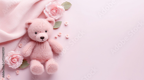 A small knitted amigurumi bear toy on a pink blanket, on a pink background. Flat lay, top view, copy space. space for text