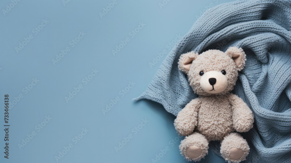 A small knitted amigurumi bear toy on a blue blanket, on a blue background. Flat lay, top view, copy space. space for text