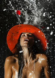 A stylish woman braves the elements, her red hat standing out against the snowy landscape as water splashes playfully around her face