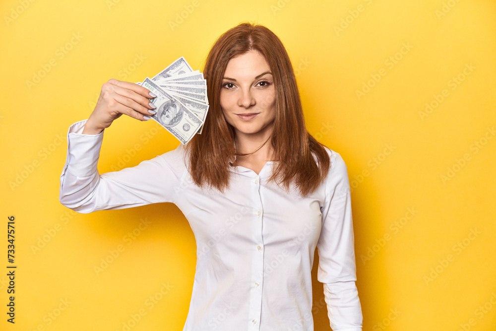 Redhead holding dollar bills, finance and wealth concept. Redhead holding dollar bills, finance and wealth concept.
