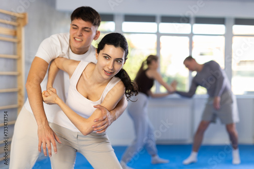 Young woman and young guy training self-defense techniques in studio..