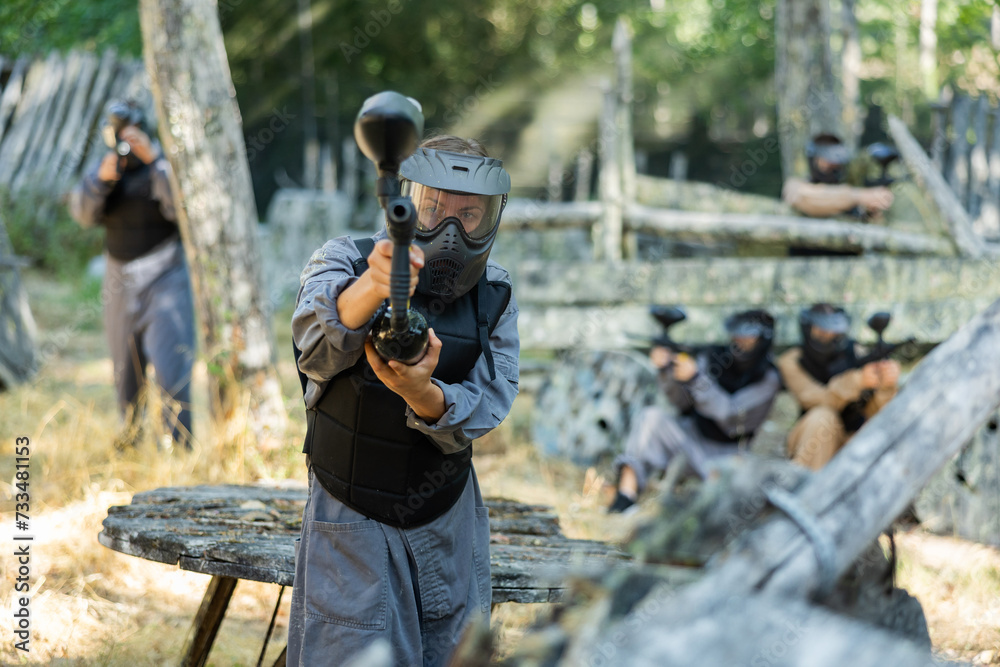 Fototapeta premium Excited paintball player in protective uniform aiming and shooting with guns