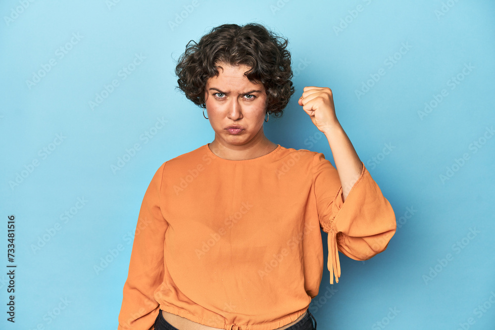 Young Caucasian woman with short hair showing fist to camera, aggressive facial expression. Young Caucasian woman with short hair showing fist to camera, aggressive facial expression.