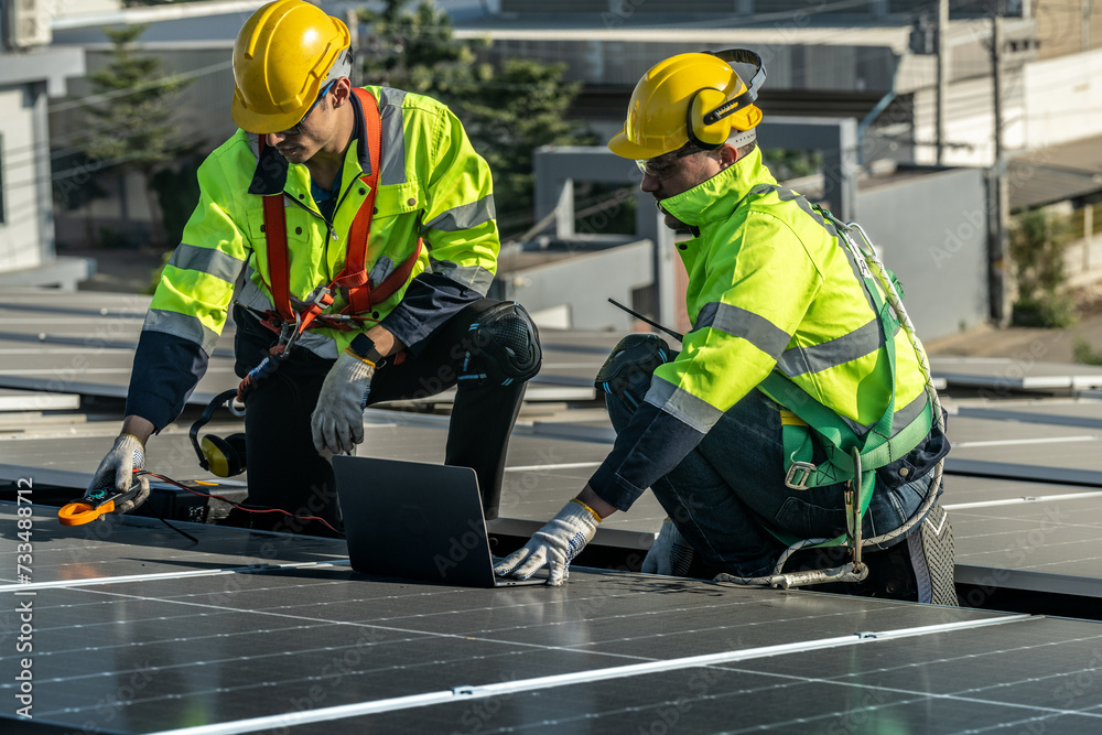 Worker Technicians are working to construct solar panels system on roof. Installing solar photovoltaic panel system. Men technicians carrying photovoltaic solar modules on roof. Worker Technicians are working to construct solar panels system on roof. Installing solar photovoltaic panel system. Men technicians carrying photovoltaic solar modules on roof.