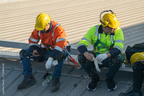 Worker Technicians are working to construct solar panels system on roof. Installing solar photovoltaic panel system. Men technicians carrying photovoltaic solar modules on roof.