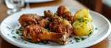 A comforting dish of fried chicken and potatoes served on a white plate, set on a wooden table, showcasing a delicious combination of meats and ingredients.