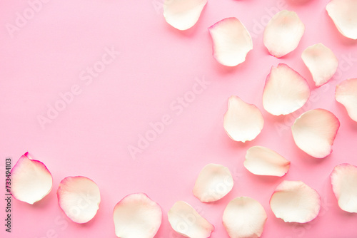 White rose petals on pastel pink background. Valentines Day or Wedding concept. Beautiful greeting card. Copy space for the text