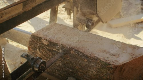 Close-up of sawmill equipment cutting a log. Timber processing and woodworking concept. Industrial machinery in action for construction and carpentry themes.