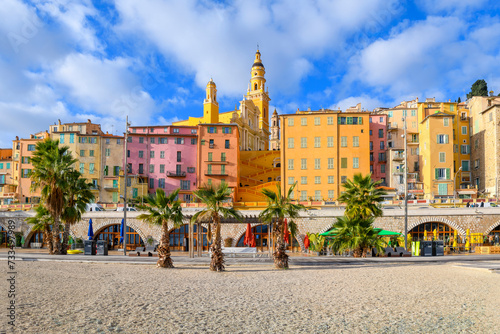 The colorful skyline including the Basilica Saint-Michael and steps to the old town above Plage des Sablettes beach and promenade in the colorful seaside town of Menton, France. photo