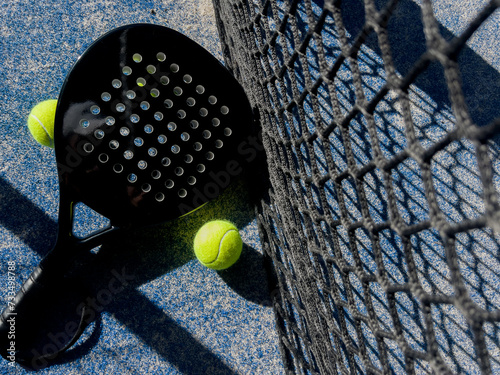 Pala de pádel con una pelota para jugar el deporte de mayor crecimiento en los últimos años a nivel mundial. Cancha de pádel en verano, el momento perfecto para practicar esta disciplina deportiva.