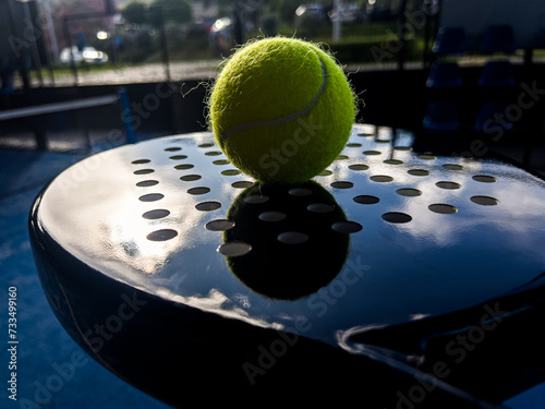 Pala de pádel con una pelota para jugar el deporte de mayor crecimiento en los últimos años a nivel mundial. Cancha de pádel en verano, el momento perfecto para practicar esta disciplina deportiva. photo