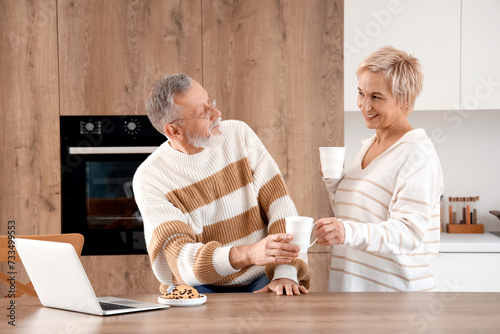 Mature couple with cups of ...