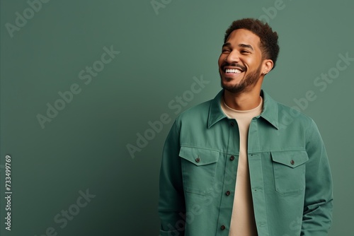 happy african american man laughing and looking away on green background