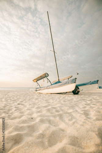 Boat on white sand on the sea coast at sunset.Sea transport. Sandy white dunes.Beach summer background.Windy weather at sea.Summer light mood. 