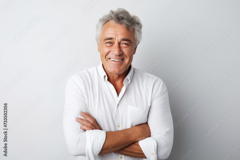 Portrait of a happy senior man standing with arms crossed against grey background Portrait of a happy senior man standing with arms crossed against grey background