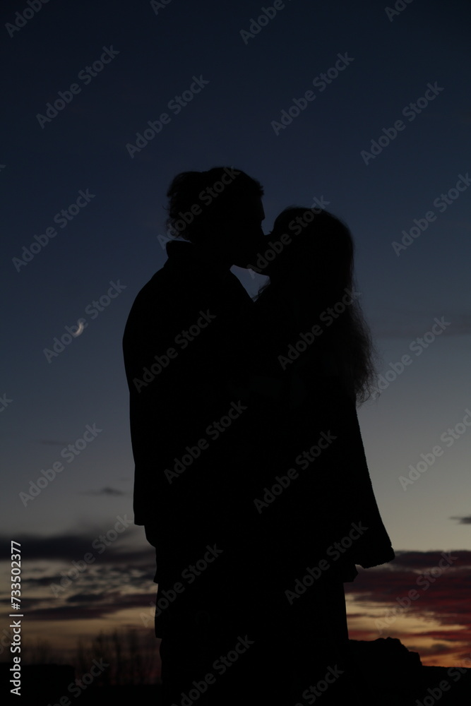 silhouette of a couple kissing on the beach